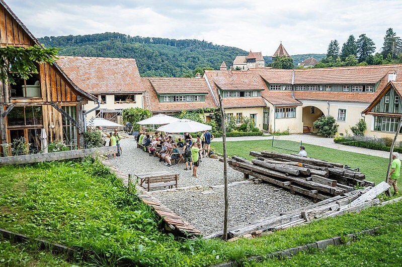 Blick eines Innenhofs, auf dem Menschen an Tischen zu sehen sind.
